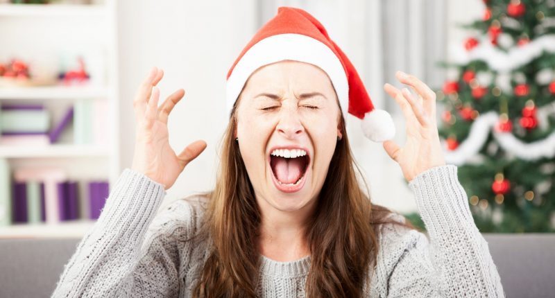 Auf dem Bild ist eine junge Frau mit Weihnachtsmütze zu sehen. Sie schreit verzweifelt, hat dabei die Augen zugekniffen, weil sie eigentlich Streit an Weihnachten vermeiden möchte.