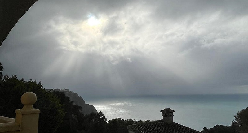 Auf dem Bild ist ein wolkenbedeckter Himmel über Spanien zu sehen. An einer Stelle bricht die Sonne durch. Ein Sinnbild für gute Laune bei schlechtem Wetter.